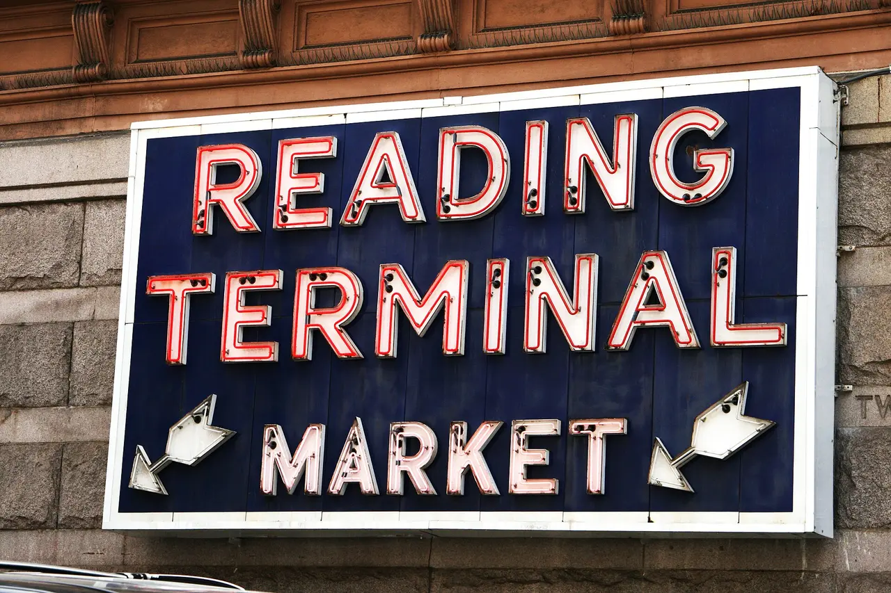 Shoppers and food counters under the signs inside Reading Terminal Market in Philadelphia