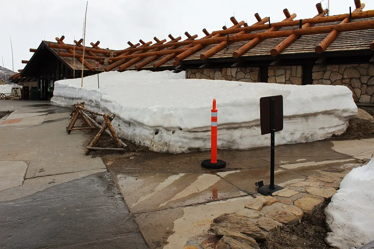 A large snowbank still standing against the Alpine Visitor Center building in Rocky Mountain National Park