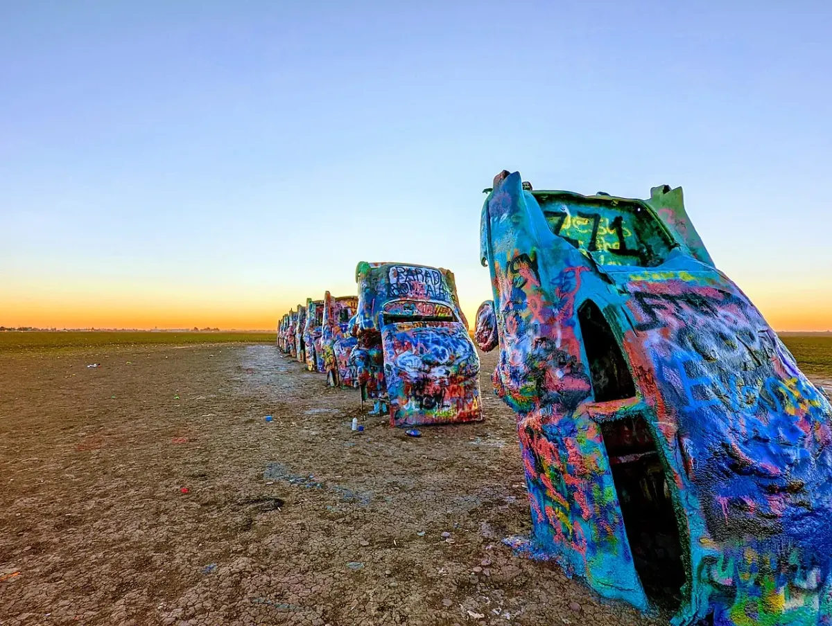 Ten graffiti-covered Cadillacs buried nose-down in a Texas field at sunrise at Cadillac Ranch