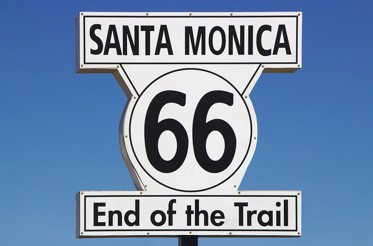 The Route 66 End of the Trail sign on the Santa Monica Pier with the ocean behind