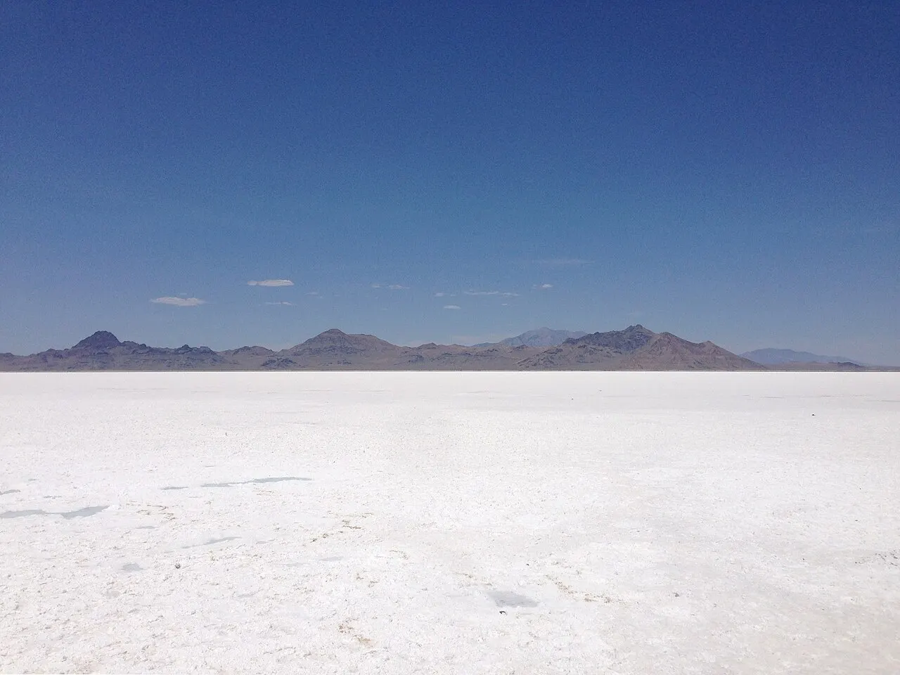 Wide view of the flat white Bonneville Salt Flats stretching toward distant mountains under a clear sky