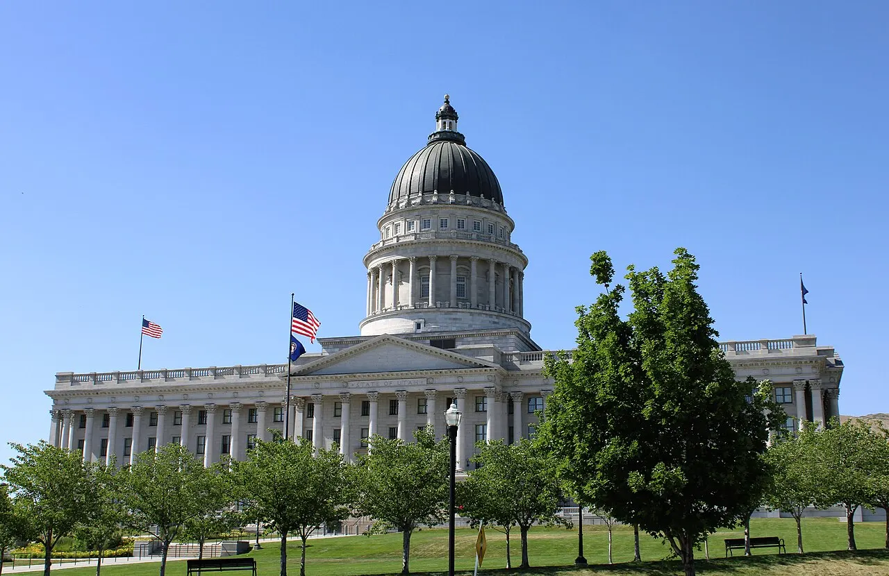 The white domed Utah State Capitol building with American flags and green lawns in front