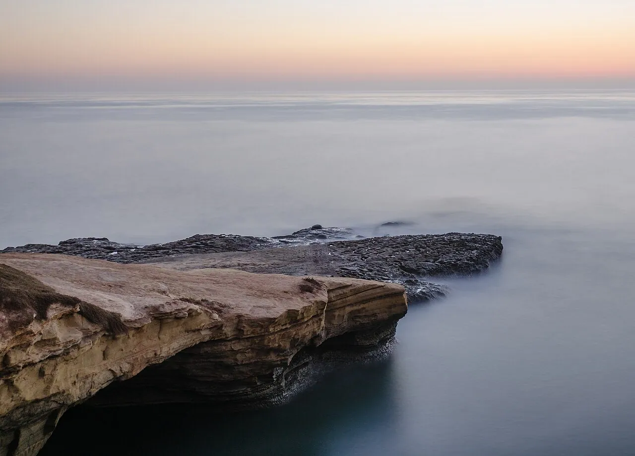 Waves breaking below the sandstone bluffs of Sunset Cliffs Natural Park at dusk