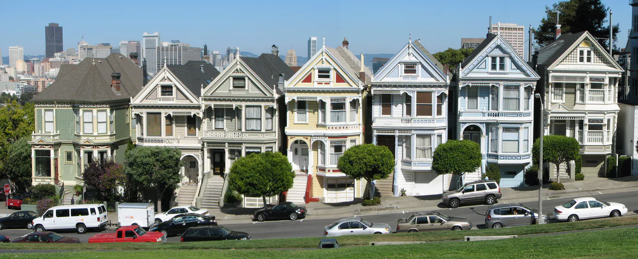 The row of Painted Ladies Victorian houses at Alamo Square with the San Francisco skyline behind