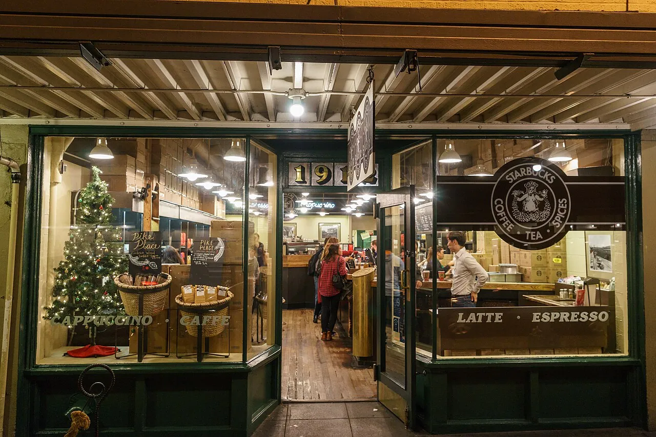 The Starbucks store at 1912 Pike Place in Seattle with its brown sign and waiting customers