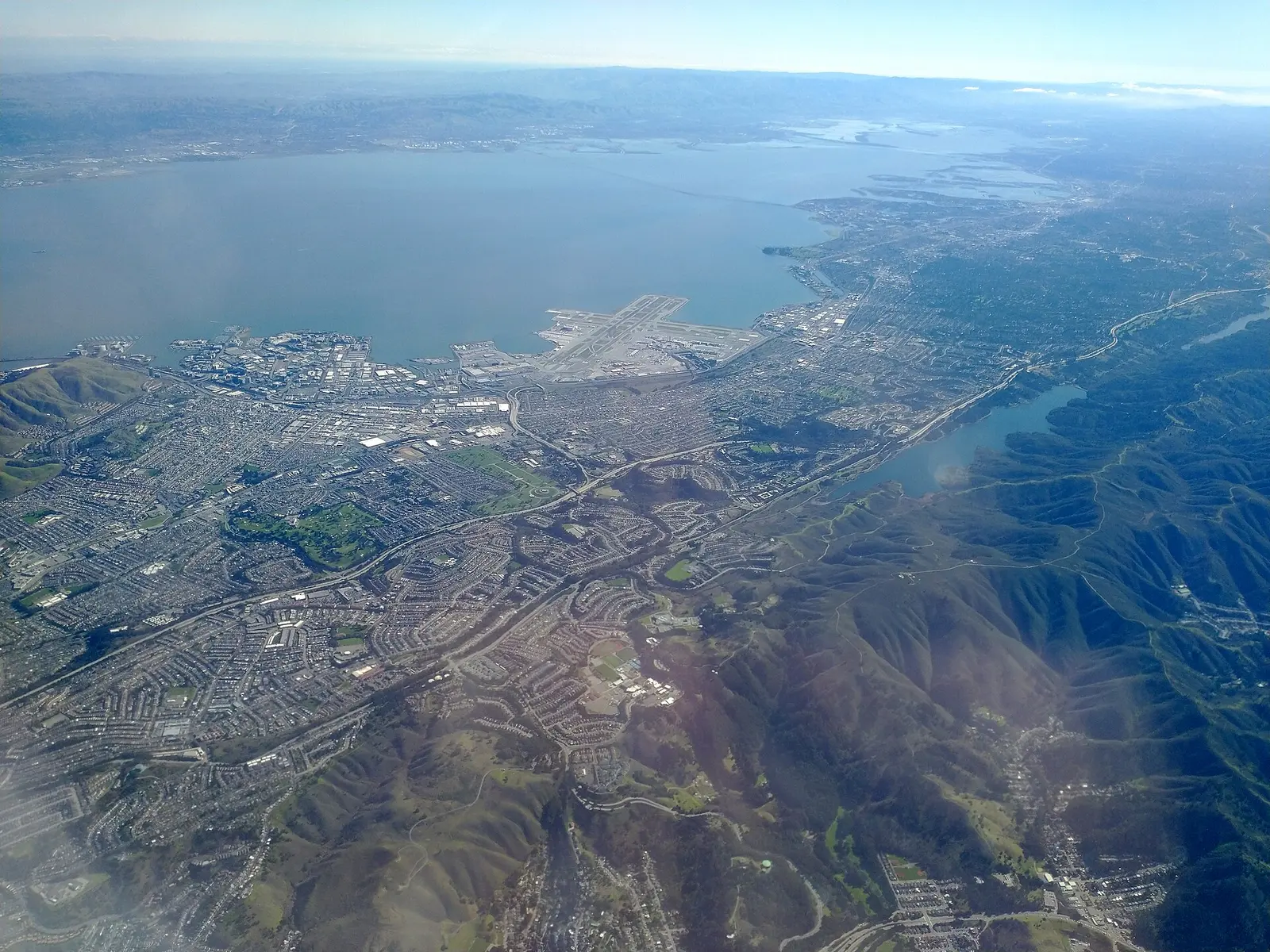 Aerial view of San Francisco International Airport terminals with the bay and Millbrae behind