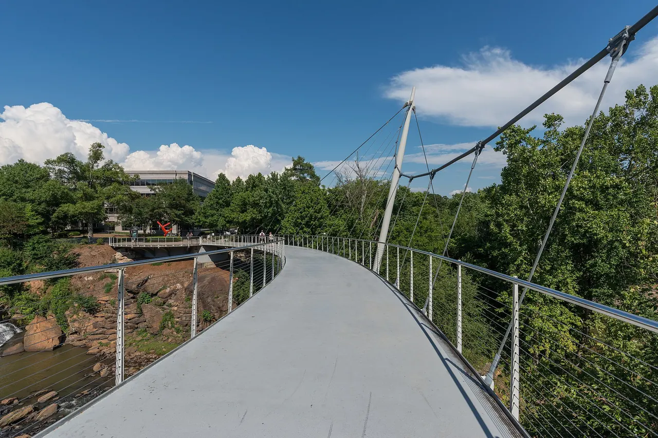 The curved Liberty Bridge pedestrian suspension bridge over the Reedy River falls in downtown Greenville