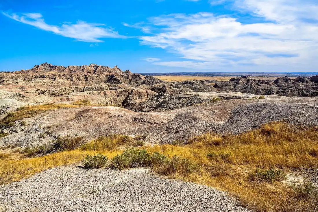 Banded badlands formations and grass under a wide South Dakota sky