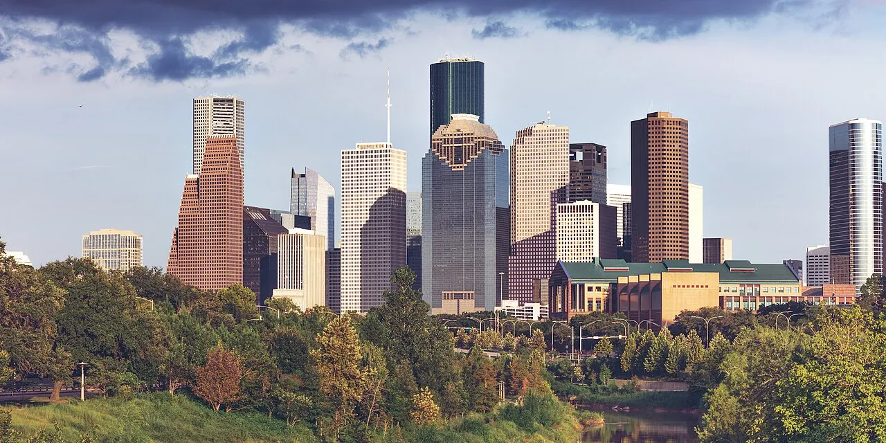 The downtown Houston skyline at dusk with office towers lit against a blue sky
