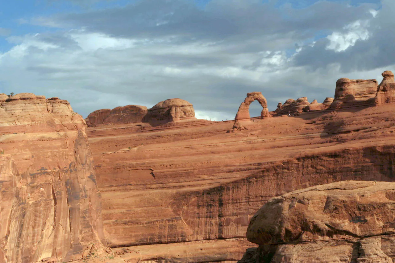 Delicate Arch standing on slickrock with the La Sal Mountains behind in Arches National Park, Utah