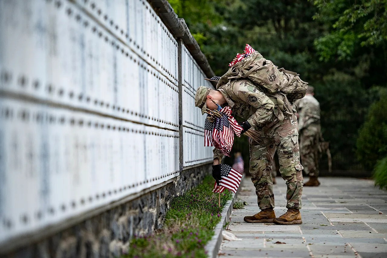 Rows of white headstones with small US flags at Arlington National Cemetery