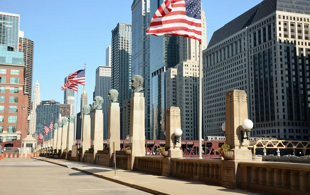Flags and sculpted busts on the Michigan Avenue bridge with skyscrapers behind