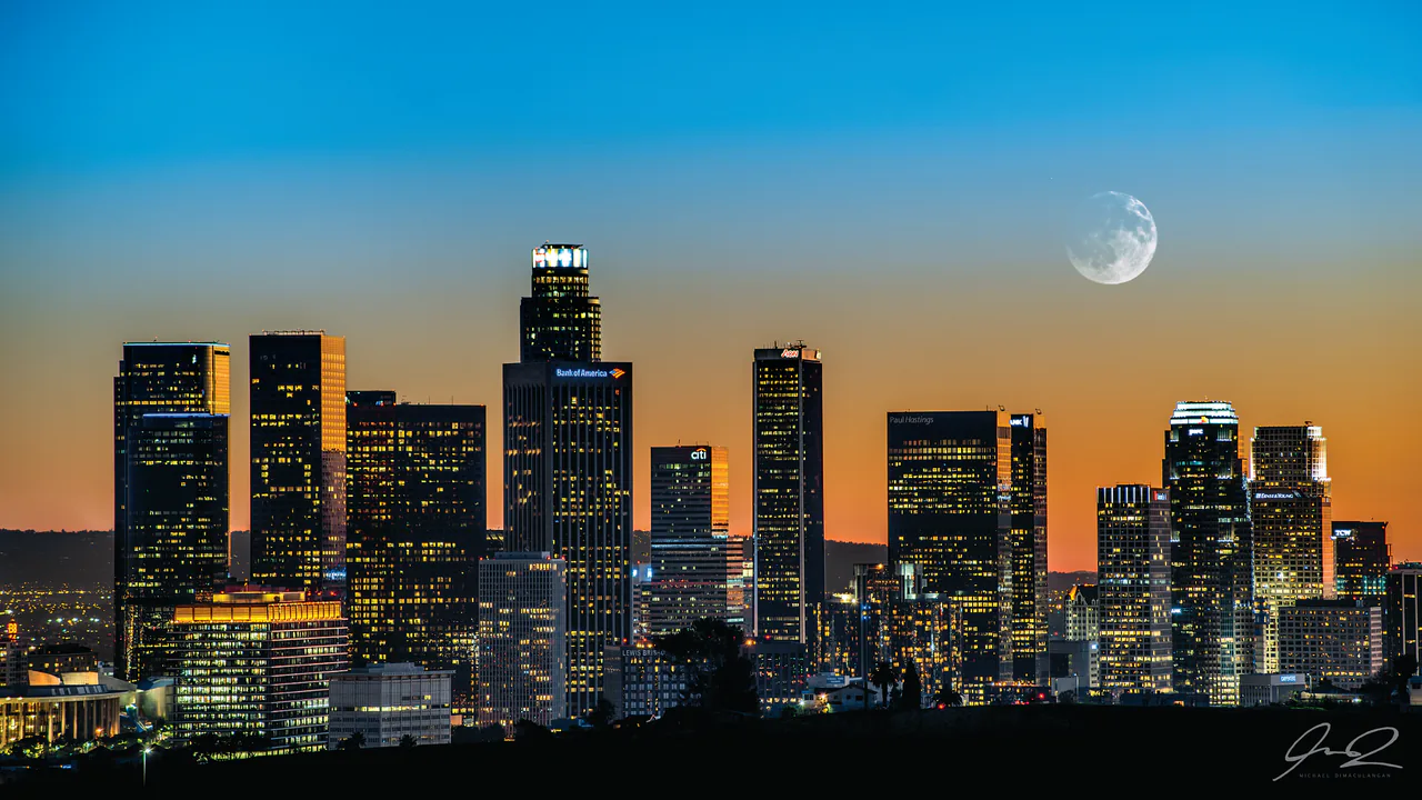 The Los Angeles skyline at dusk with lit towers and the hills behind