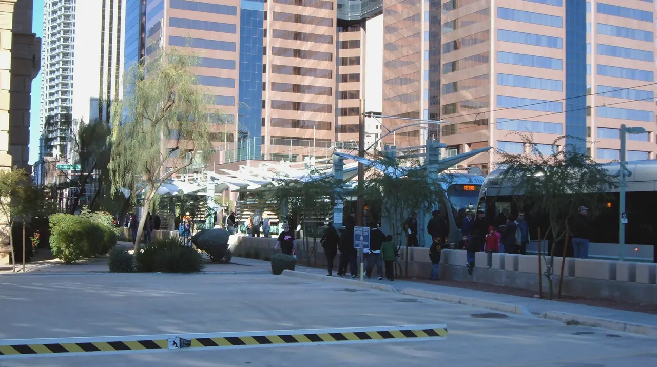 A Valley Metro light rail train at a downtown Phoenix station with palm trees along the platform