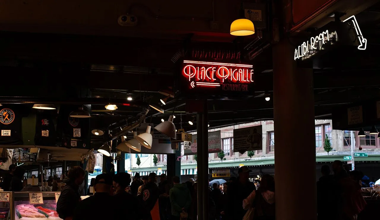 Neon restaurant signs glowing under the covered arcade at Pike Place Market in Seattle