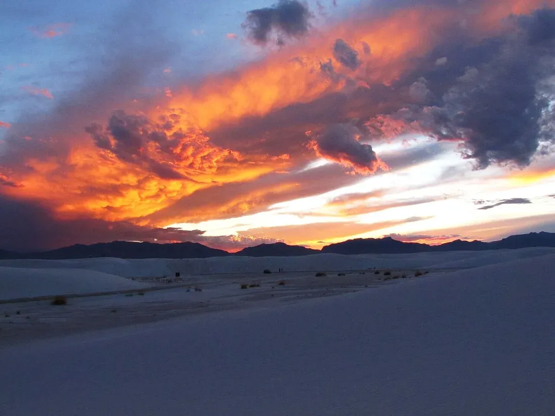 Orange sunset sky above white sand dunes
